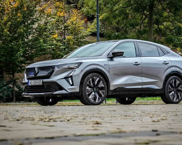 Nowy Renault Rafale, elegancki SUV coupe, prezentuje się na tle jesiennej zieleni i ceglanej ściany.
