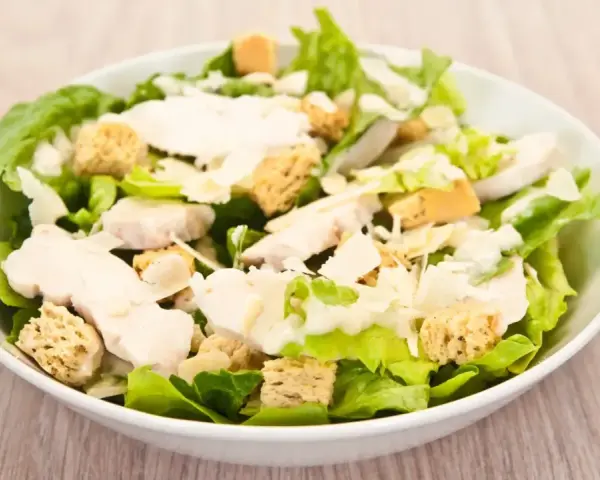 Salade César appétissante avec poulet, croûtons dorés et copeaux de parmesan. Un classique des salade cesar ingredient.