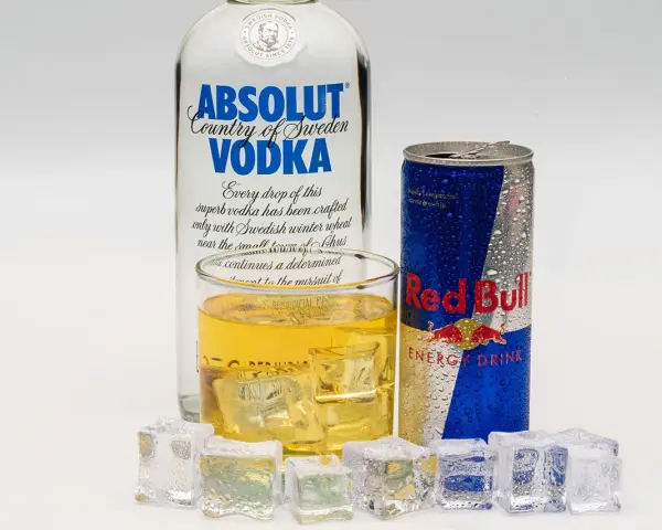 Szklanka z drinkiem, puszka Red Bulla i butelka wódki Absolut – klasyczny energetyk z alkoholem.