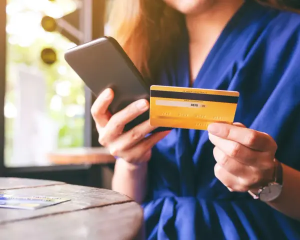 Frau hält Smartphone und goldene Kreditkarte für Online-Shopping.