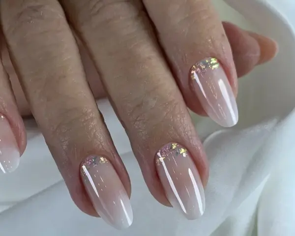 Dłonie z eleganckim baby boomer z brokatem. Delikatny manicure podkreśla naturalne piękno.