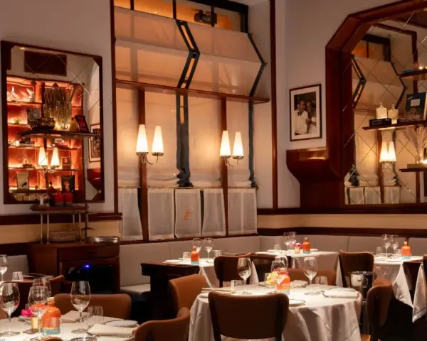 Tavoli apparecchiati in un ambiente elegante, ideale per scoprire i migliori ristoranti Milano. Luci soffuse e dettagli raffinati creano un'atmosfera accogliente.