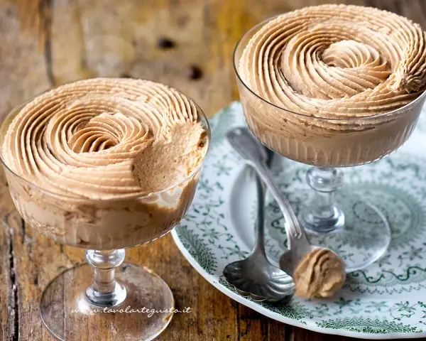 Due coppe di deliziosa mousse al caffè, guarnite a spirale, su un piatto decorato.