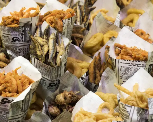 Una variedad de fritura de pescado, incluyendo camarones, boquerones y calamares, servidos en conos de papel.