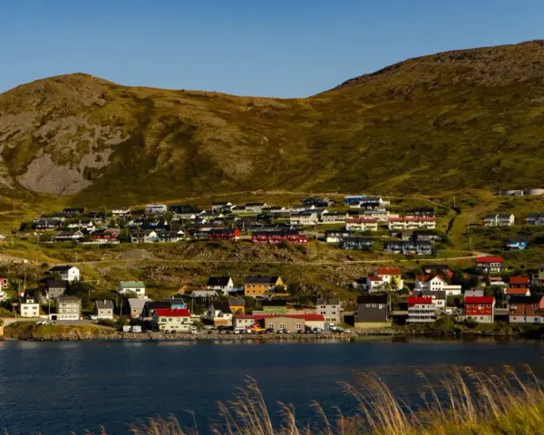 Kolorowe domy nad fiordem, w tle górzysty krajobraz. Nordcamp Norwegia, malownicza wioska rybacka.