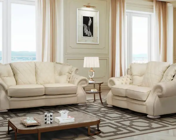 Elegante soggiorno con divani chiari, un tavolino e una lampada. Il tessuto sembra il miglior tessuto per divani antimacchia, ideale per una casa raffinata.