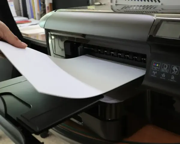 Dłoń wkłada papier do drukarki. To nie jest elementem eksploatacyjnym drukarki laserowej, lecz jej podstawowym materiałem.