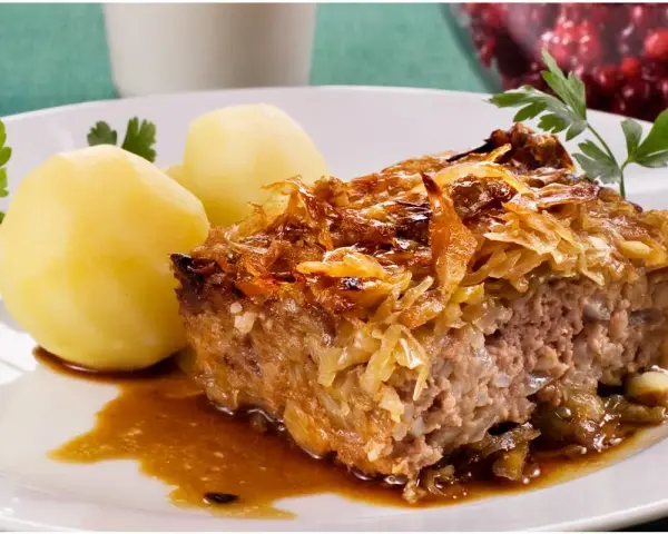 En bit kålpudding med kokt potatis och en skvätt sås. Perfekt för ett klassiskt kålpudding recept.