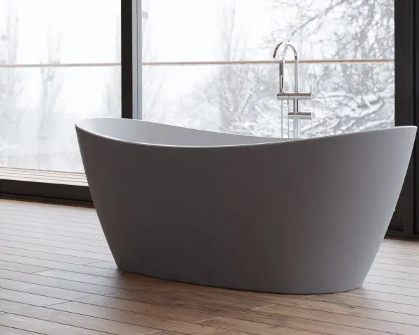 Baignoire îlot moderne, avec robinetterie chromée, devant une grande fenêtre donnant sur un paysage hivernal. Les inconvénients de ce type de baignoire sont son encombrement et la nécessité d'une installation spécifique.
