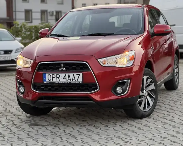 Czerwone Mitsubishi ASX z przodu, z tablicą rejestracyjną OPR 4AA7.