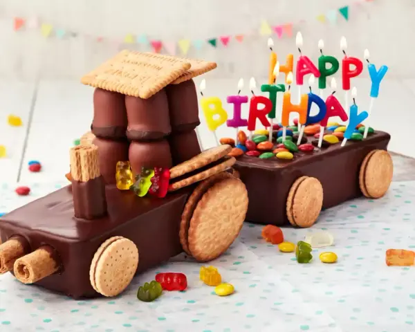 Schokoladen-Traktor-Torte, die man leicht selber machen kann, mit bunten Kerzen und Gummibärchen verziert.