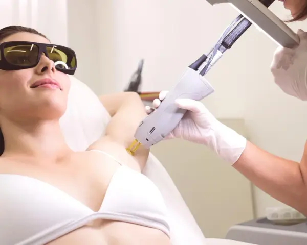 Depilacja laserowa pach jak się przygotować? Kobieta w okularach ochronnych poddaje się zabiegowi usuwania owłosienia laserem.