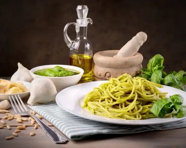 Pyszny makaron z pesto ze słoika, podany z bazylią, czosnkiem, parmezanem i orzeszkami pinii.