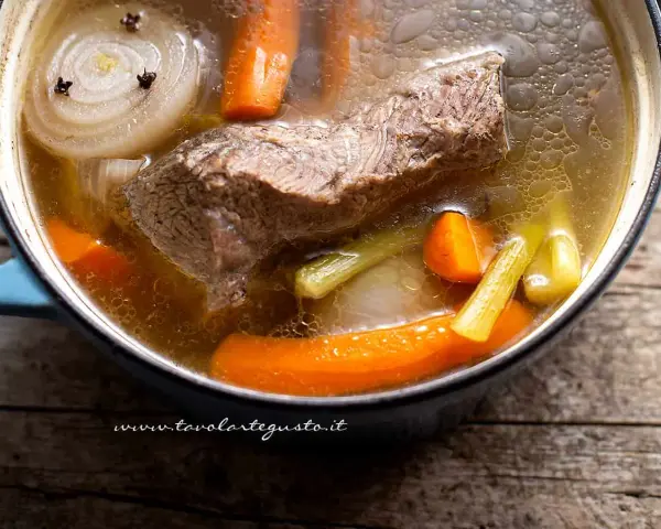 Un pezzo di carne succulenta cuoce lentamente in un brodo di carne ricco, con carote, sedano e cipolla.