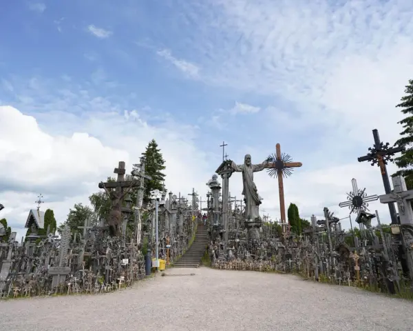 A vast mountain of crosses, with a statue of Jesus at its peak, stands under a cloudy sky.