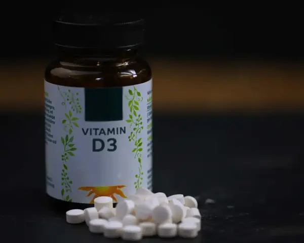 Flasche mit Vitamin D3 und Pillen. Wann einnehmen? Am besten mit einer Mahlzeit, um die Aufnahme zu verbessern.