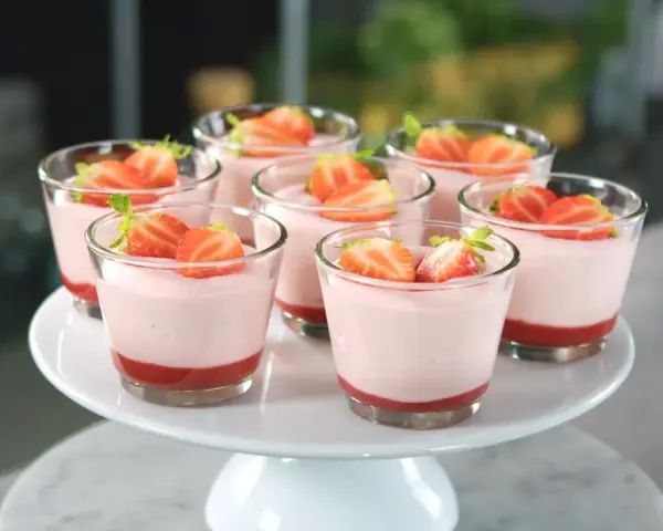 Deliziosi dolci al cucchiaio alla fragola, serviti in bicchierini trasparenti e guarniti con fragole fresche.