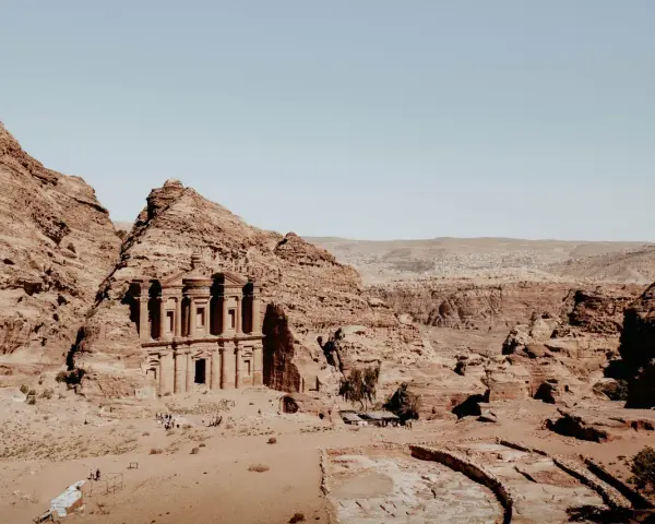 The ancient jordan ruins of Petra, carved into sandstone cliffs, stand majestically under a clear blue sky.