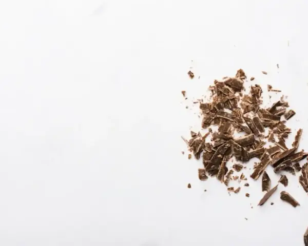 Éclats de grué de cacao sur fond blanc, rappelant les nombreux bienfaits de cet ingrédient naturel.