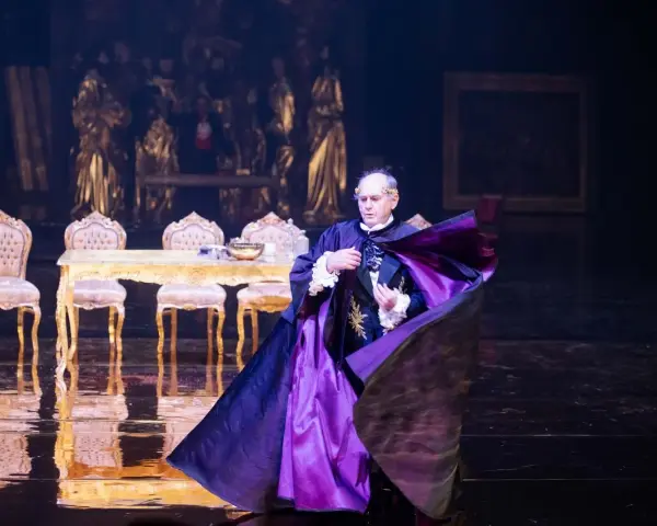 Aktor w purpurowej pelerynie, w teatralnej scenografii, budzi pytanie: misterium co to?