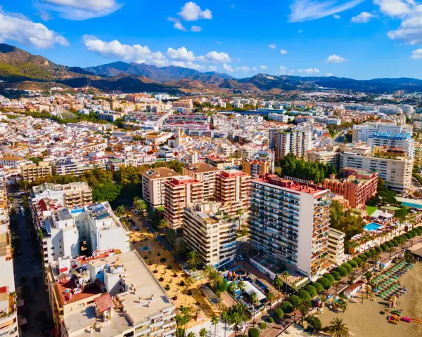 Widok z lotu ptaka na nadmorskie miasto Marbella, z górami w tle. Widać plażę, hotele i budynki mieszkalne.