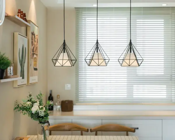 Trzy wiszące lampy w kształcie diamentu nad stołem w salonie.