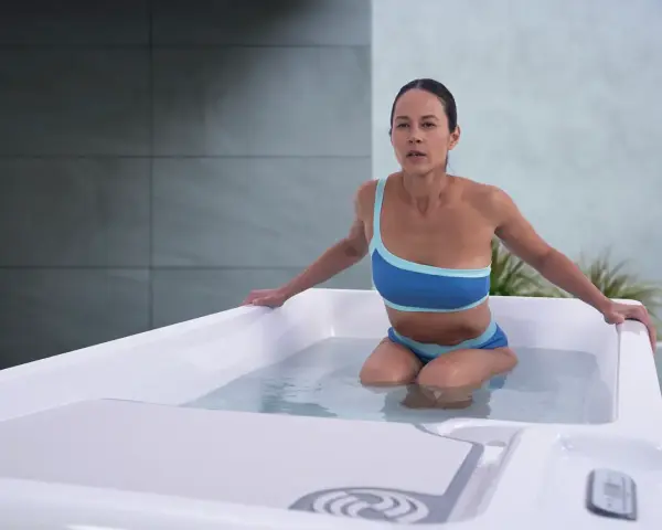 Kobieta w bikini w wannie z wodą, przygotowująca się do terapii metodą cieplo zimno.