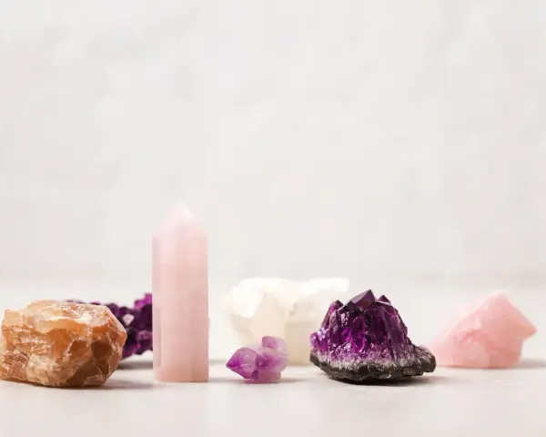 Colección de cristales energéticos: amatista, cuarzo rosa y calcita anaranjada, dispuestos sobre una superficie clara.