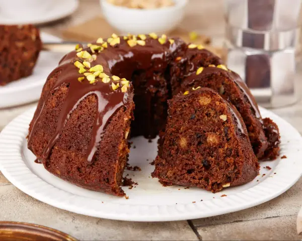 Pyszna babka na oleju, polana czekoladą i posypana pistacjami, czeka na kawę.