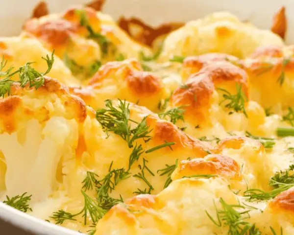 Coliflor al horno gratinada con queso y hierbas frescas. Un plato reconfortante y delicioso.
