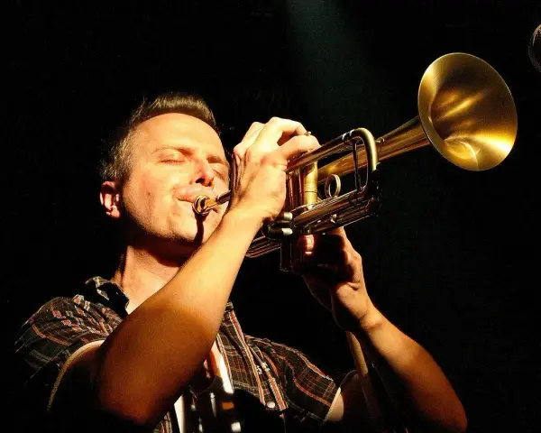 Muzyk gra na trąbce, zamykając oczy. Czy to synkopa co to? Muzyka jazzowa.