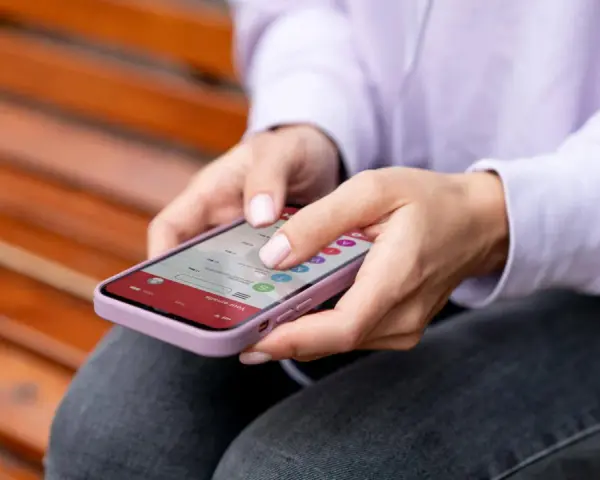 Dłonie kobiety obsługują smartfon, czując subtelne wibracje haptyczne przy każdym dotknięciu ekranu.