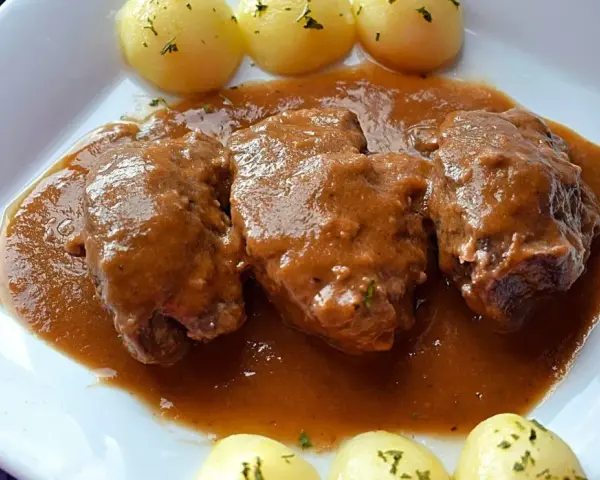 Carrilleras al vino tinto, tiernas y jugosas, bañadas en una rica salsa, acompañadas de patatas cocidas. Un plato casero que reconforta.