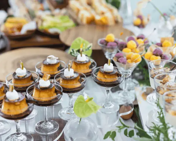 Köstliche kleine Karamellpudding-Desserts mit Sahne und Früchtebällchen – tolle Buffet Ideen für jede Feier.