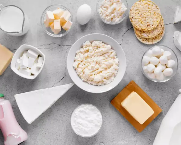 Różnorodne produkty bogate w wapń: mleko, sery, jogurt, masło, jajko i wafle ryżowe.