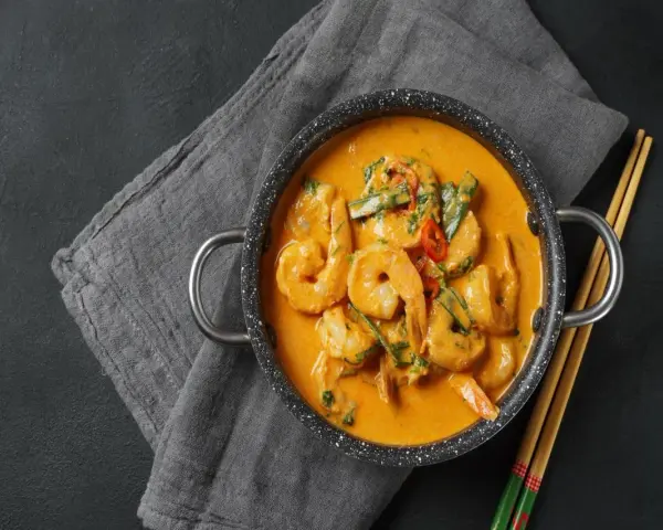 Aksamitne tajskie curry z krewetkami, podane w garnuszku z pałeczkami.