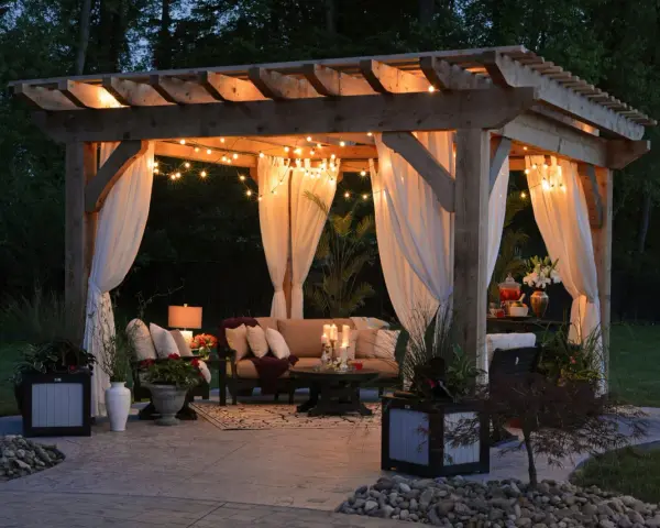 Mysig altan med pergola, draperade gardiner och stämningsfull belysning. Perfekt inspiration för din egen altanbelysning.