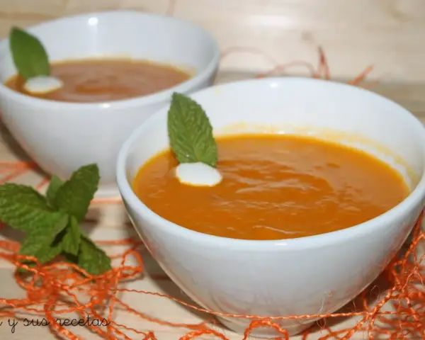 Dos cuencos blancos con crema de calabaza naranja, decorados con menta y un toque de nata.