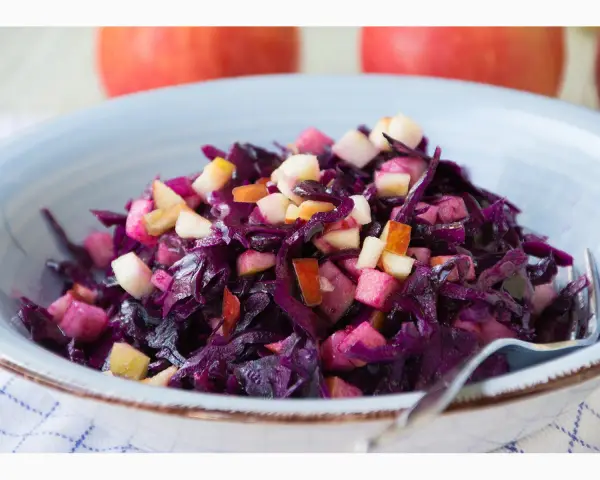 Schüssel mit leckerem rotkohl salat, garniert mit Apfelstücken.