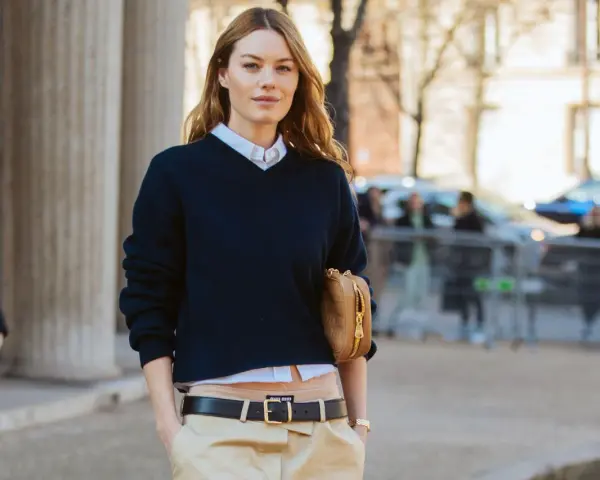 Modello con maglione blu scuro, camicia bianca e pantaloni beige. Un'idea su come vestirsi per uscire con stile.