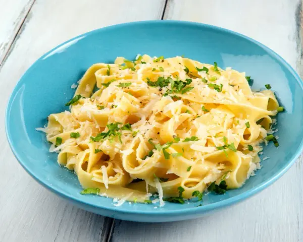 Fettuccine al burro e parmigiano, uno dei sughi per pasta più semplici e gustosi, guarnito con prezzemolo fresco.