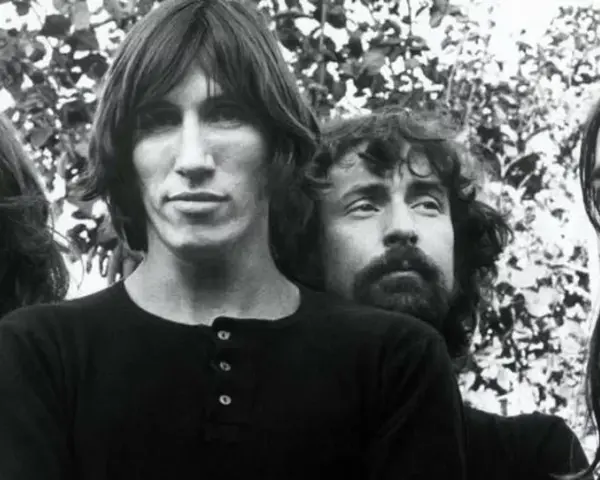 Quatre musiciens aux cheveux longs, dans un style musical Pink Floyd, posent devant un feuillage.
