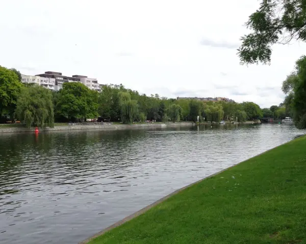 Grüne Ufer am Landwehrkanal Berlin mit Bäumen, Gebäuden und Menschen, die sich auf der Wiese entspannen.
