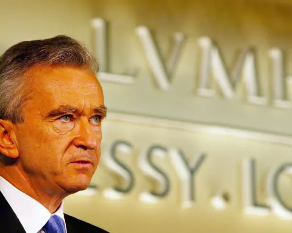 Bernard Arnault, proprietario Dior, guarda pensieroso. Sullo sfondo, il logo LVMH.