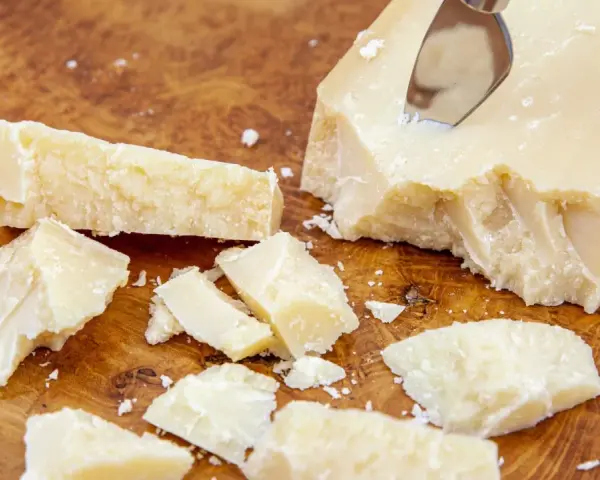 Kawałki parmezanu, znanego też jako Grana Padano, na drewnianej desce.