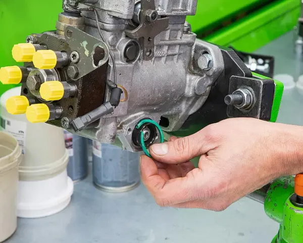 Hand replaces a green O-ring on a Bosch Einspritzpumpe, part of the process to einspritzpumpe reparieren.