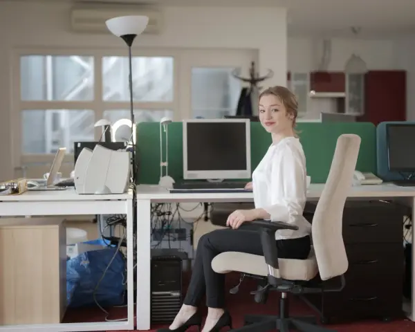 Uśmiechnięta sekretarka przy biurku w szkole. Zastanawiasz się, ile zarabia sekretarka w szkole?