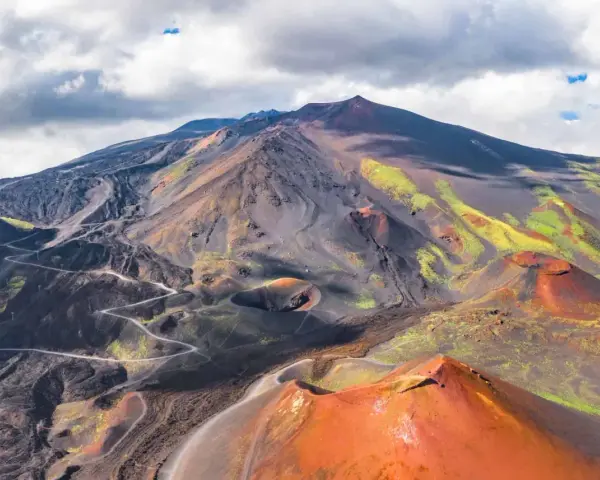 Vue aérienne de l'Etna, avec ses cratères rouges et ses pentes noires et vertes.