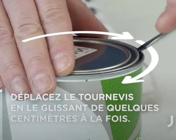 Main tenant un tournevis, on montre comment ouvrir un pot de peinture en faisant levier sur le couvercle.