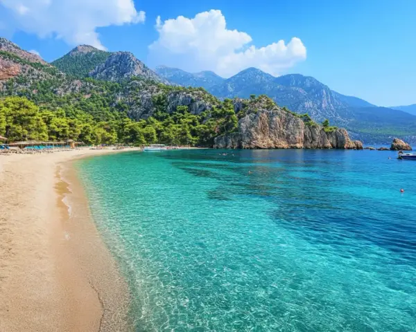 Piękna plaża w Turcji, Kusadasi, z turkusową wodą, górami i sosnami. Idealne miejsce na wakacje.